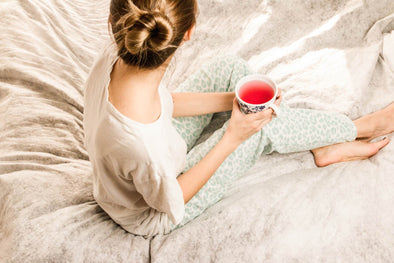 woman in bed drinking sleep tea to help her sleep better